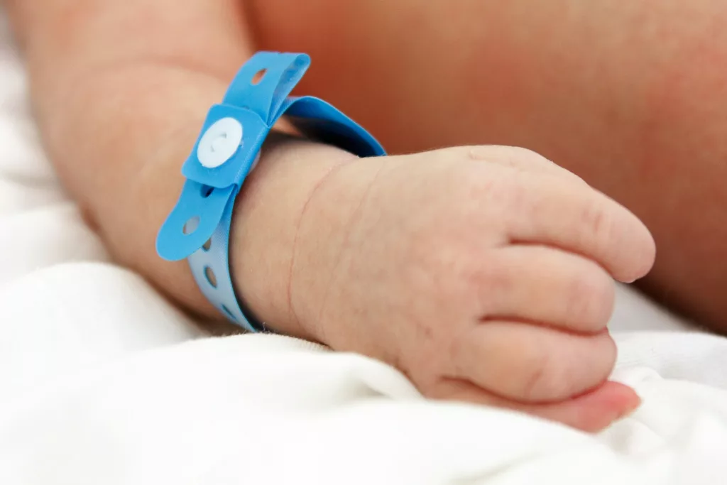 newborns hand with a blue tag in maternity hospital